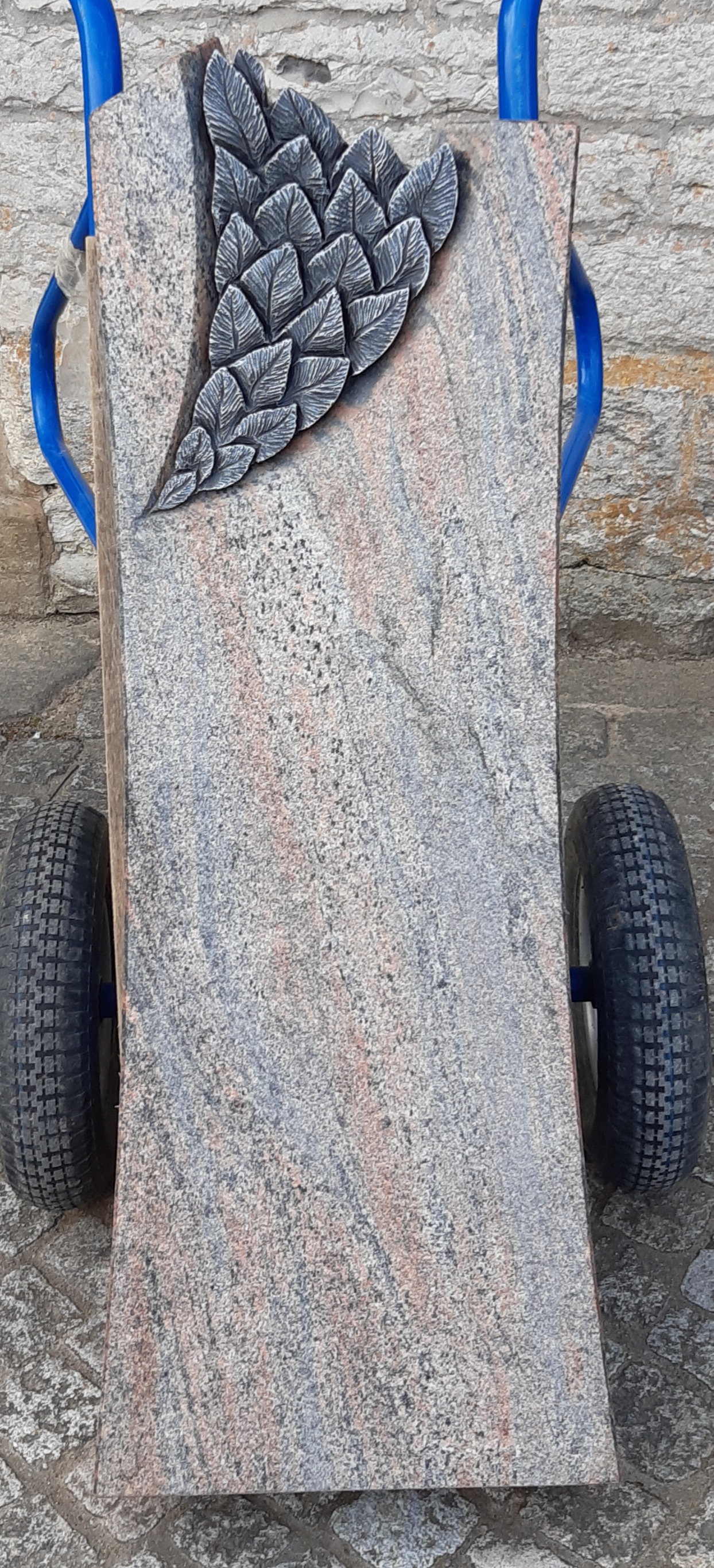 Grauer Grabstein mit Blätterrelief