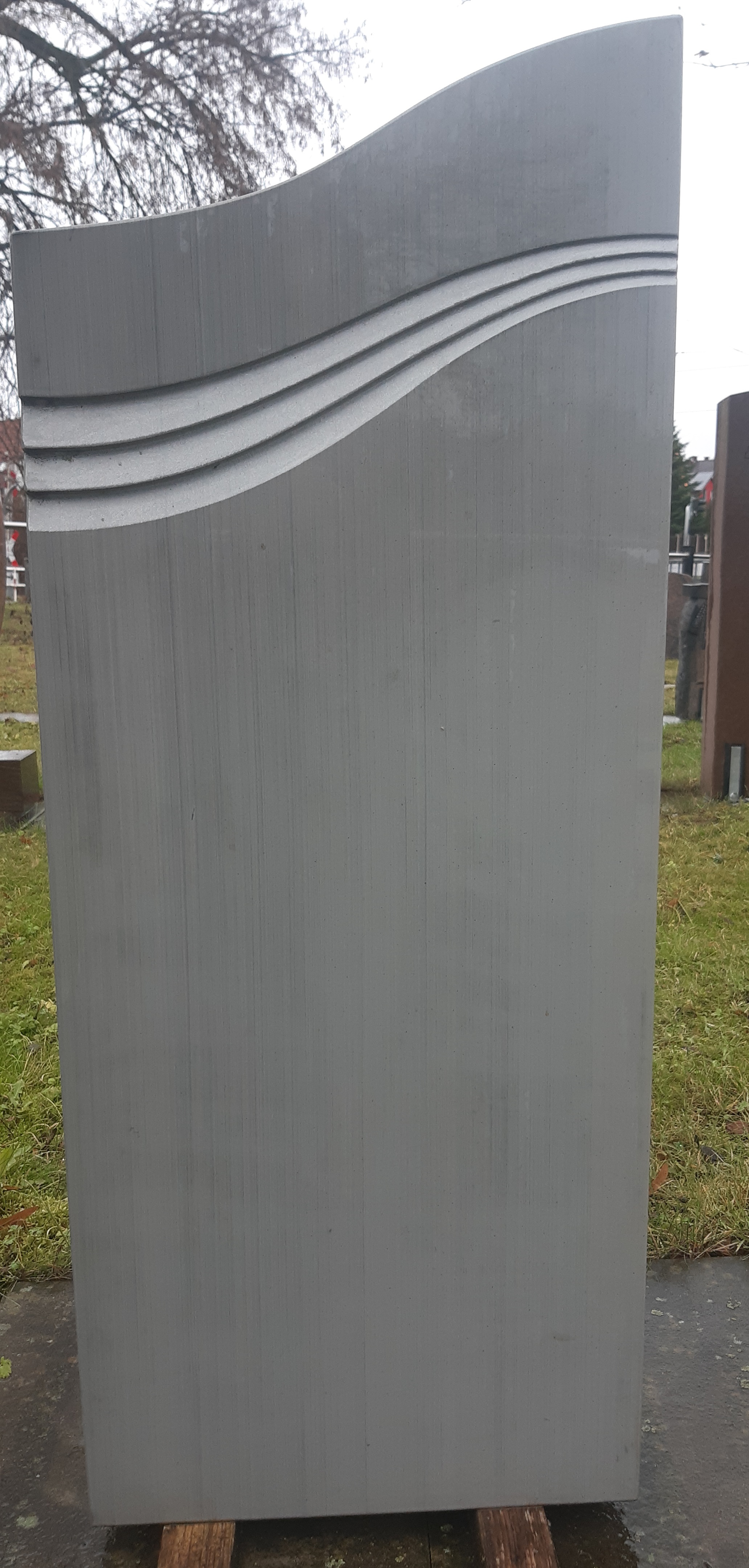 Grauer Grabstein mit Wellenrelief