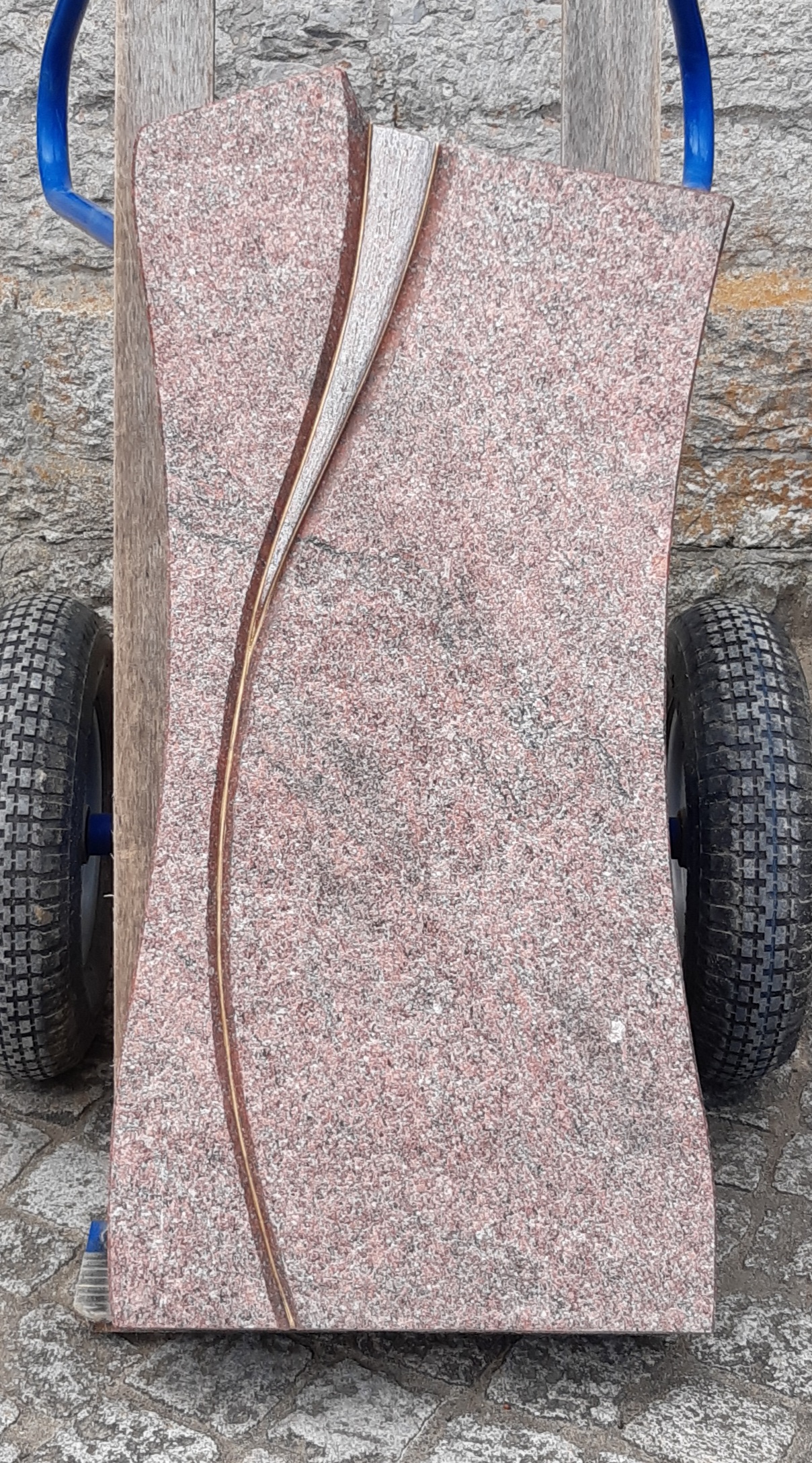 Roter Grabstein mit geschwungenem Relief